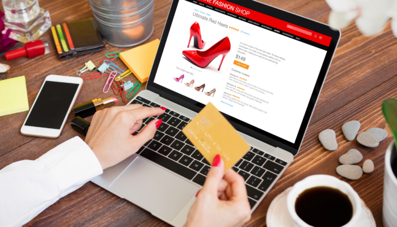 picture of a female with a credit card in her hand. She's looking at a website with shoes. 